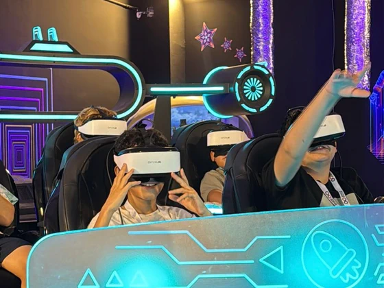 שורת ילדים עם משקפי VR בטבעת ה־UFO, אחד מרים יד
