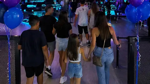 A family walks into the hall between balloon columns, a mother and daughter hand in hand