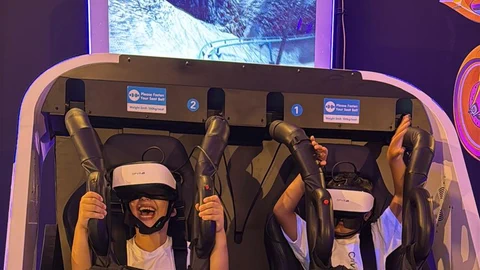 שני ילדים חגורים במכונת ה־360, עם משקפי VR וידיים למעלה