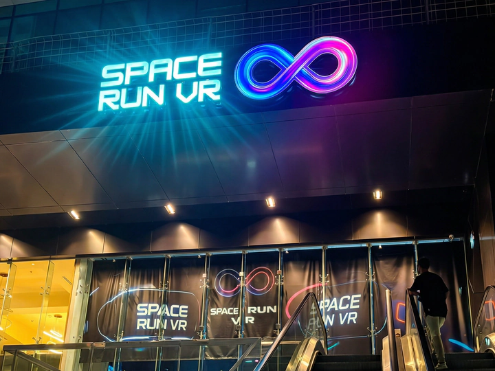 The Space Run VR storefront at night: the lit SPACE RUN VR sign with the infinity logo above the glass front, escalators in front of it